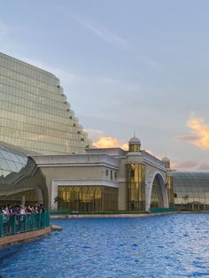 people are standing at the edge of a swimming pool in front of a large building