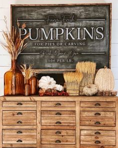 an old dresser with pumpkins and other items on it, sitting in front of a chalkboard