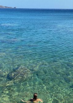 a person swimming in clear blue water on a sunny day with an island in the distance