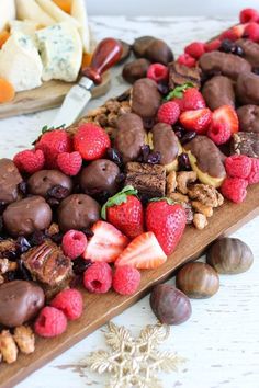 a wooden board topped with chocolate covered strawberries and nuts