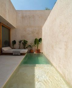 an indoor swimming pool in the middle of a room with plants and furniture around it