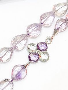 Stunning quality lilac Amethyst stones, faceted and shaped like teardrops, finished with a large 925 silver clasp set with faceted green amethyst and lilac amethyst stones arranged as a flower.Measuring approximately 22" in length. All jewellery is packed in beautiful gift pouches.The item will be securely packaged and sent promptly after payment is received. Please note if you require a quicker method of delivery we can also arrange that.Thank you so much for looking at my shop!Please contact m Faceted Amethyst Briolette Gemstones, Teardrop Amethyst Necklaces With Gemstone Accents, Purple Amethyst Teardrop Gemstone, Purple Teardrop Amethyst Gemstone, Faceted Lavender Briolette Jewelry, Lavender Amethyst Teardrop Necklace, Lavender Teardrop Amethyst Necklace, Teardrop Amethyst Gemstone Beads Necklaces, Amethyst Gemstones For Jewelry Making In Teardrop Shape