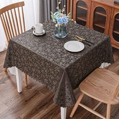 a dining room table covered with a black tablecloth and two white plates on top of it