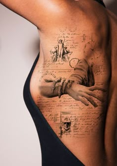 a woman's back with tattoos on it and writing all over the place where her hand is placed