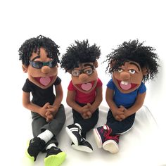 three black stuffed animals sitting next to each other on a white surface with their mouths open