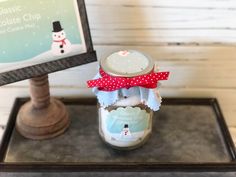 a mason jar with a red bow on it sitting on a tray next to a sign