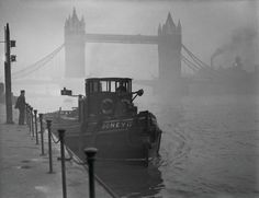 there is a boat that is sitting in the water next to a fence and tower bridge