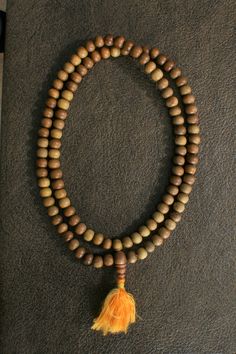 Sandalwood is a prized and fragrant wood that has been used for thousands of years. This mala is made from Indian sandalwood and contains exactly 108 beads. Many people wear malas as decorative necklaces but the main spiritual function is to count prayers when chanting mantras. 108 is a sacred number in Hinduism, Buddhism, and yogic traditions and practitioners may use a mala to chant a mantra exactly 108 times. Necklace length: 28 in (71 cm) Bead diameter: 0.3 in (~8 mm) Free shipping within th Brown Wooden Beads Holistic Necklace, Holistic Brown Mala With Wooden Beads, Holistic Brown Necklaces With Wooden Beads, Wooden Round Beads Jewelry For Meditation, Brown Wooden Beads Necklace For Meditation, Brown Wooden Beads Spiritual Mala, Spiritual Necklace With Wooden Beads, Spiritual Wooden Beads Necklace, Spiritual Brown Wooden Beads Mala