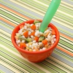 a bowl filled with rice and veggies next to a green plastic straw sticking out of it