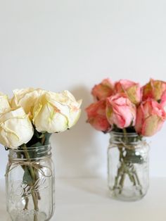 two mason jars filled with pink and white roses