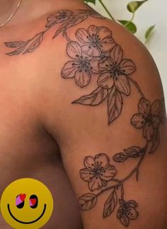 the back of a woman's shoulder with flowers on it and a smiley face