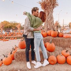 a man and woman embracing in front of pumpkins