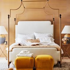 a bedroom with a bed, two stools and lamps on either side of the bed