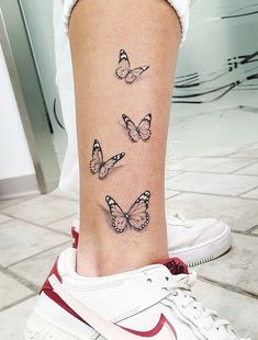 a woman's foot with three butterflies on the left side of her leg,