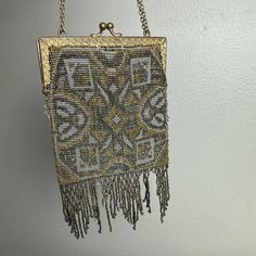 This is an antique Edwardian era purse from the late 1900s. It is made of steel beads in gold and silver tones. The purse has an Art Nouveau design. The bag is in good vintage condition. There is some separation of fabric at the hinges. The fringe at the bottom is missing beads. Please see the photos for condition details and measurements. Gold Bohemian Evening Bag, Bohemian Gold Evening Bag, Gold Bohemian Evening Bag Handmade, Antique Beaded Bags For Vintage Events, Handmade Victorian Gold Bags, Antique Beaded Rectangular Evening Bag, Antique Gold Evening Bag, Vintage Gold Bags With Gold Beads, Antique Handmade Gold Evening Bag