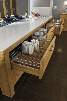 an open drawer in the middle of a large kitchen counter with dishes and utensils