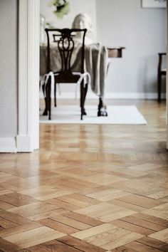 a wooden floor with a chair and table in the background