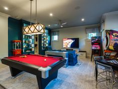 a game room with a pool table, arcade machine and other entertainment equipment in it