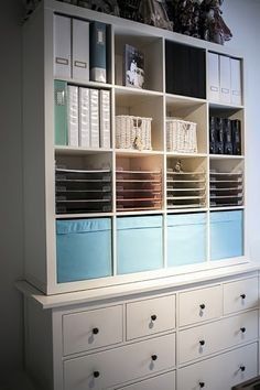 a white bookcase filled with lots of books on top of a wooden dresser next to a window