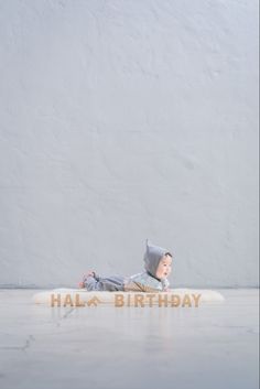 a small child laying on top of a white pillow with the words hala birthday written across it