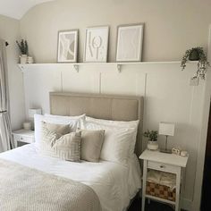 a bed with white sheets and pillows in a bedroom next to two pictures on the wall