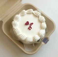 a white cake with two hearts on it in a box, ready to be eaten