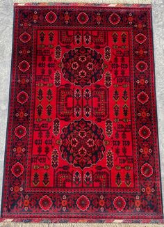 a red rug with an intricate design on the bottom and sides, in different colors