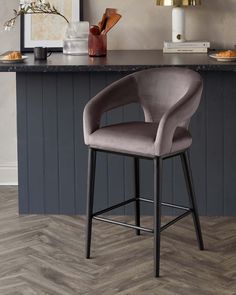 a grey bar stool sitting in front of a counter top next to a wooden floor