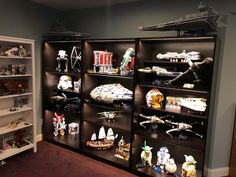 a collection of star wars action figures on display in a room with shelves full of toys