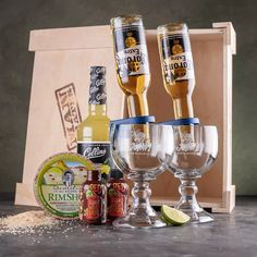 three wine glasses, two empty bottles and some condiments in front of a wooden box