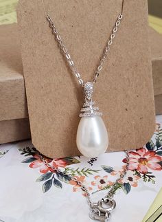 "*Genuine grade AAA best lustrous big size freshwater pearl teardrop 11x15mm *Natural white color pearl, untreated, undyed *Entirely sterling silver. Rhodium plated on surface for tarnish resistance. *Pendant bail accented with cubic zirconia. *Safely packed in a jewelry box. *Adjustable chain length between 16\" and 18\" See the matching earrings: https://www.etsy.com/listing/614786400 See other design in my store: http://www.etsy.com/shop/JWJewelryBox Please contact me if you have any comment. Affordable Sterling Silver Pearl Necklace Gift, Cubic Zirconia Necklace With Pearl Pendant, Elegant Sterling Silver Pearl Necklace With Teardrop Pendant, Teardrop Pearl Pendant With Cubic Zirconia, White Sterling Silver Pearl Necklace With Teardrop Pendant, White Gold Cubic Zirconia Pearl Pendant Necklace, Pendant Bails, Original Bags, Tahitian Pearls