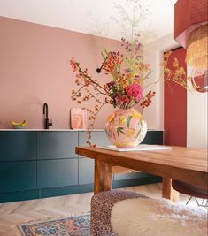 a dining room table with flowers in a vase on top and other decorations around it