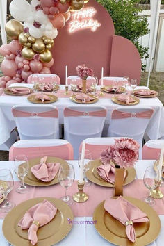 a table set up for a party with pink and gold plates, napkins, flowers and balloons