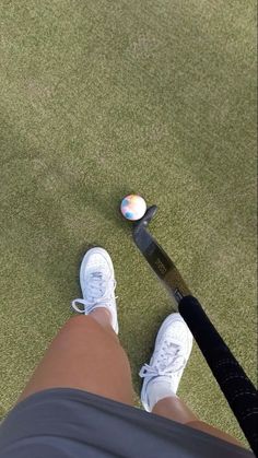 a person with white tennis shoes standing next to a racket and ball on the ground