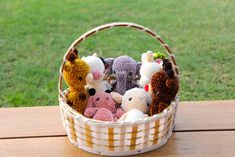 a basket filled with stuffed animals sitting on top of a wooden table next to grass