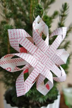 a paper snowflake ornament hanging from a christmas tree with red and white designs