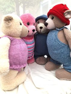 three teddy bears wearing sweaters and hats sitting next to each other on a window sill