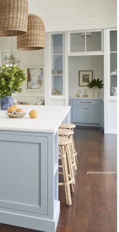 a kitchen with blue cabinets and white counter tops, hanging baskets over the island in front of the sink