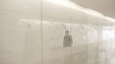 a man standing in front of a white wall with frosted glass on the walls