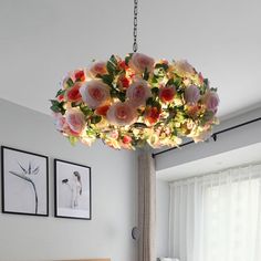 a chandelier with flowers hanging from it's ceiling in a bedroom next to a bed