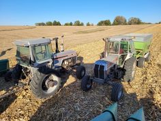 three farm tractors are parked in a field