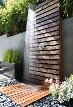 an outdoor shower with water flowing from the faucet and wooden planks on the ground