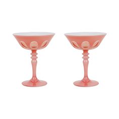 two pink glass goblets sitting side by side on a white background, one is empty