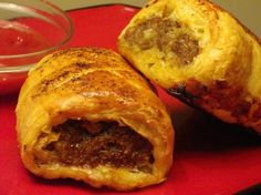 sausage rolls the australian way on a red plate next to a small bowl of sauce