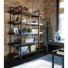 a bookshelf filled with lots of books next to a brick wall in a room