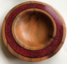 a wooden bowl with red speckles on the bottom and sides, sitting on a white surface