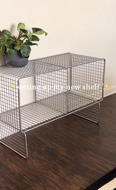 a metal shelf sitting on top of a wooden floor next to a potted plant