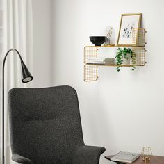 a living room with a chair, table and shelf on the wall next to it