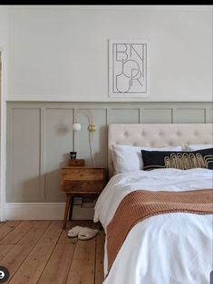 a white bed sitting in a bedroom next to a wooden dresser and lamp on top of a hard wood floor