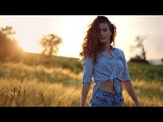 a woman walking through tall grass with her hands in her pockets